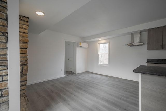unfurnished living room with wood-type flooring and a wall mounted air conditioner