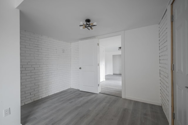 empty room with hardwood / wood-style flooring and brick wall