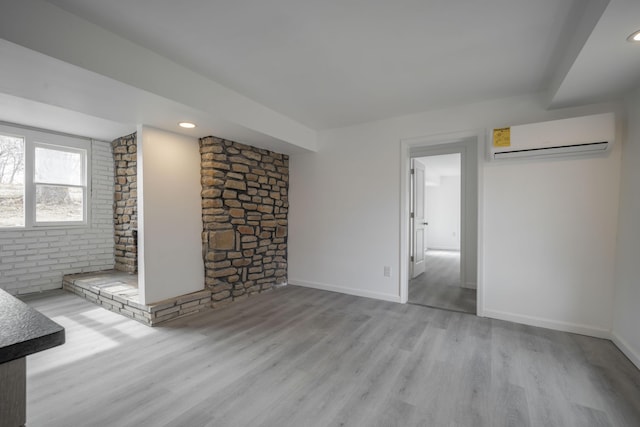 unfurnished living room with a wall unit AC and light wood-type flooring