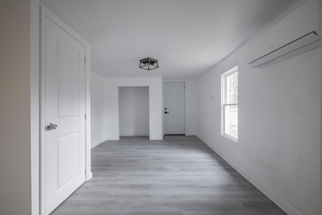 corridor with light hardwood / wood-style floors and an AC wall unit