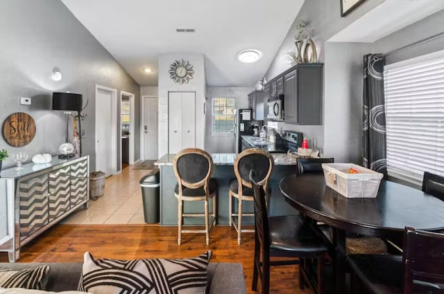 kitchen with light tile patterned flooring, vaulted ceiling, appliances with stainless steel finishes, gray cabinets, and kitchen peninsula