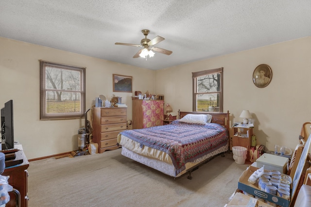 carpeted bedroom featuring ceiling fan and a textured ceiling