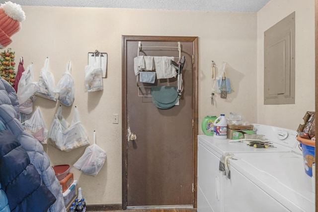 clothes washing area featuring electric panel, washer and clothes dryer, and a textured ceiling