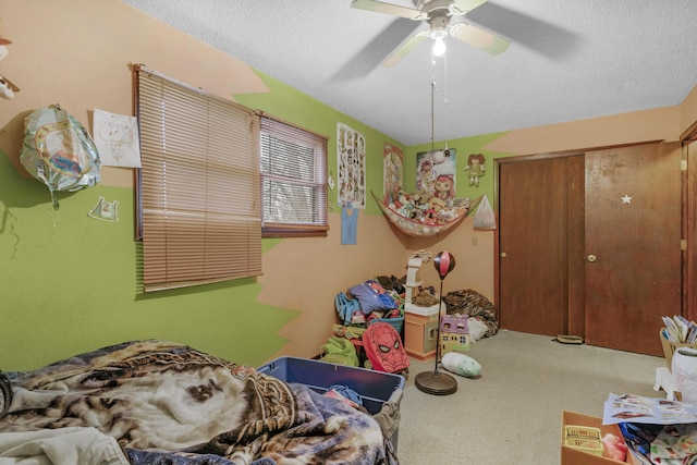 bedroom featuring ceiling fan, carpet floors, a closet, and a textured ceiling