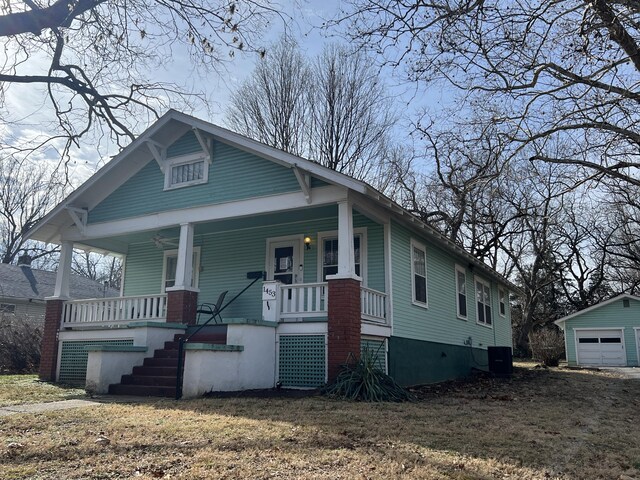 bungalow with central AC, a garage, an outbuilding, covered porch, and a front lawn