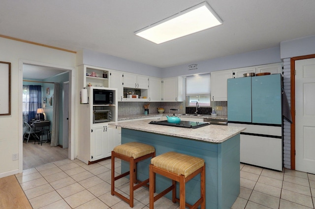 kitchen with white cabinetry, a center island, a breakfast bar, and black appliances