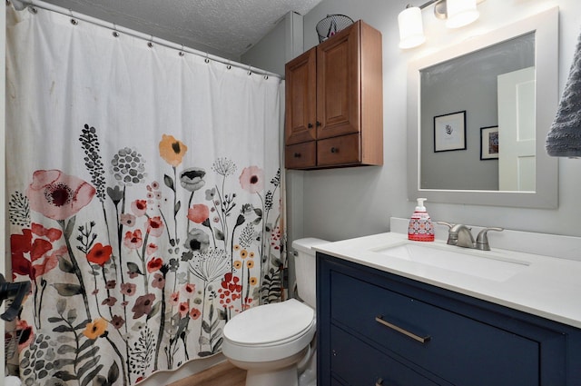 bathroom featuring walk in shower, vanity, toilet, and a textured ceiling