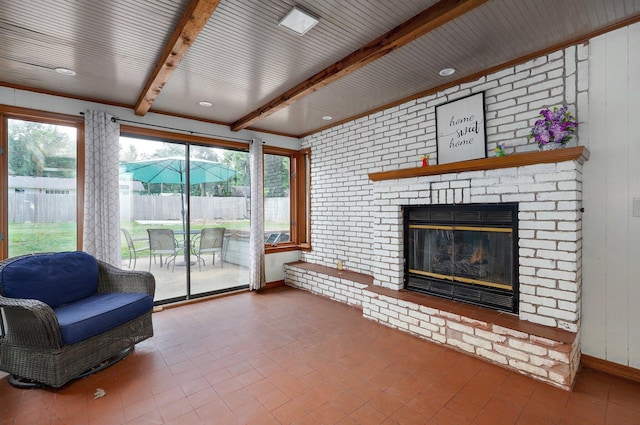 living room featuring a brick fireplace, beam ceiling, wooden walls, and brick wall