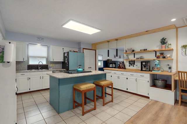 kitchen featuring sink, a breakfast bar, white cabinetry, fridge, and a kitchen island