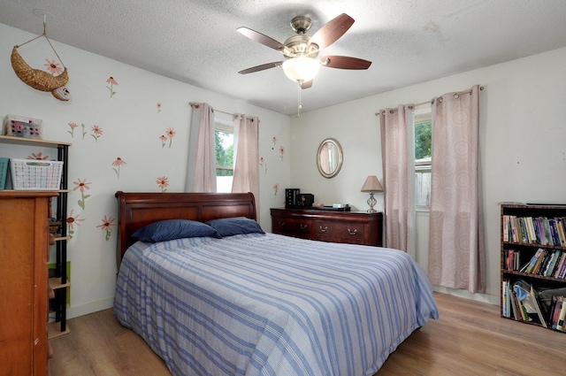 bedroom with ceiling fan, light hardwood / wood-style floors, and a textured ceiling