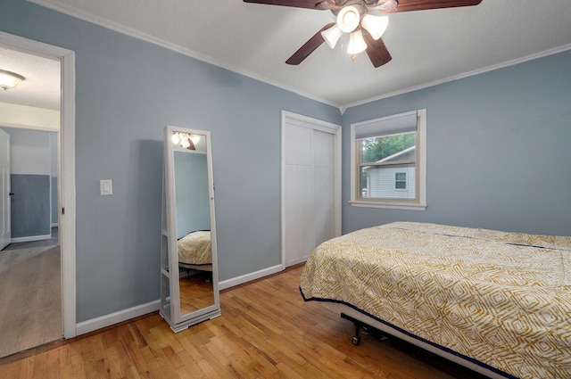 bedroom with crown molding, ceiling fan, light hardwood / wood-style floors, and a closet