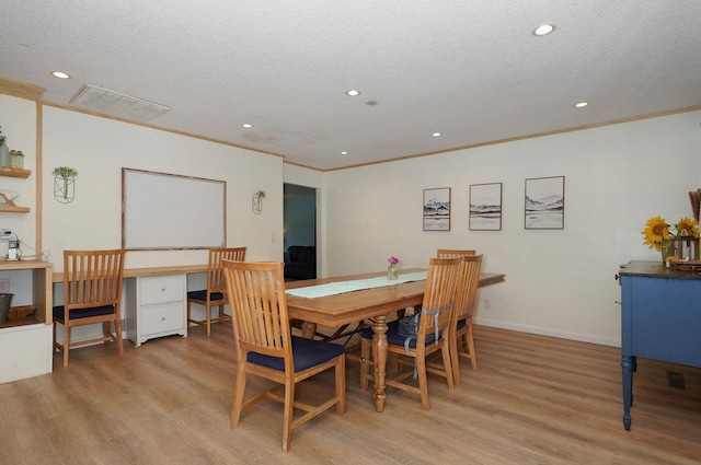 dining room with light hardwood / wood-style flooring, ornamental molding, and a textured ceiling