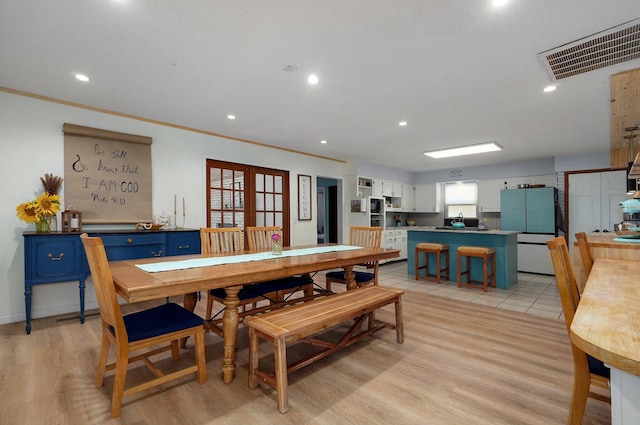 dining space featuring ornamental molding, light hardwood / wood-style floors, and french doors