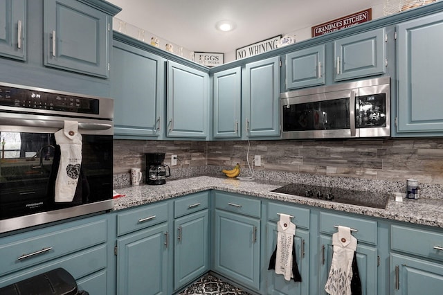 kitchen featuring light stone countertops, decorative backsplash, blue cabinetry, and appliances with stainless steel finishes