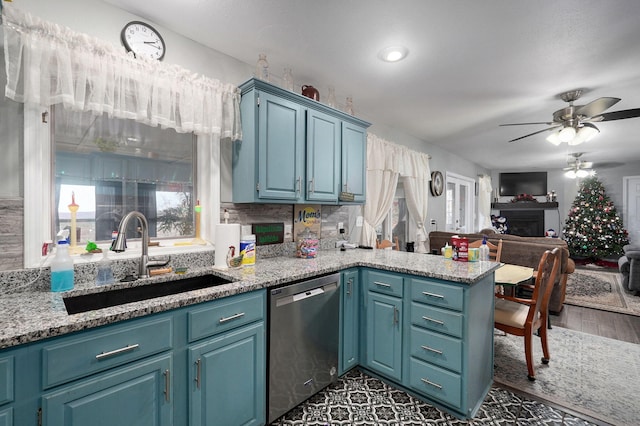 kitchen featuring blue cabinetry, stainless steel dishwasher, sink, and a wealth of natural light