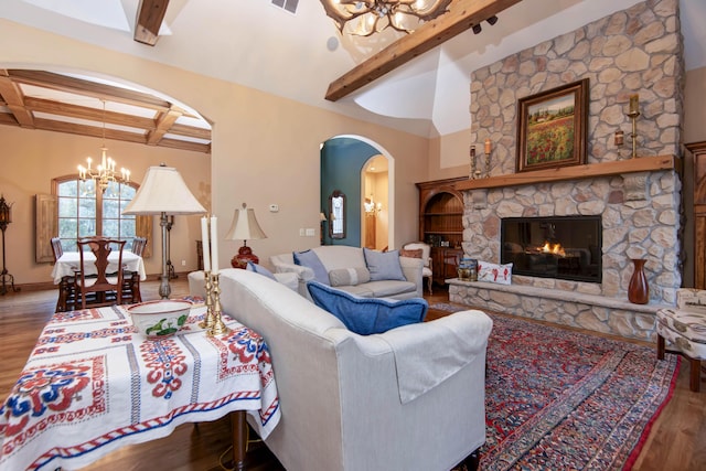 living room featuring vaulted ceiling with beams, hardwood / wood-style floors, a fireplace, and an inviting chandelier