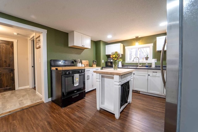 kitchen featuring dark hardwood / wood-style floors, black range oven, white cabinets, wooden counters, and hanging light fixtures