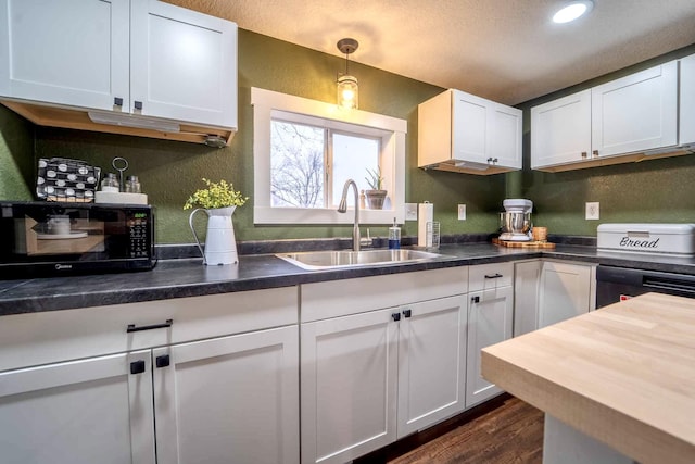 kitchen featuring white cabinetry, decorative light fixtures, sink, and dark wood-type flooring