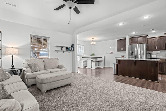 living room featuring dark hardwood / wood-style flooring and ceiling fan with notable chandelier