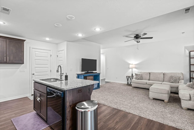 kitchen with dishwasher, sink, light stone counters, dark brown cabinetry, and a center island with sink