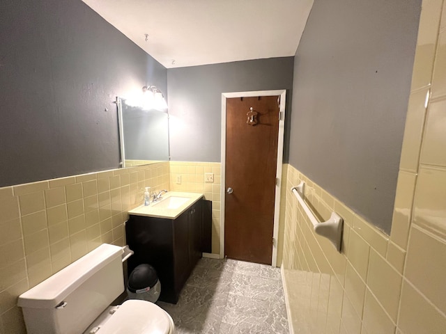 bathroom featuring vanity, toilet, and tile walls