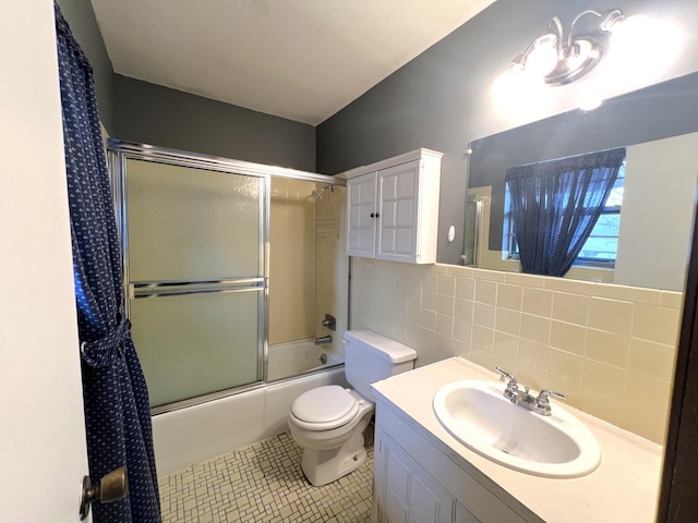 full bathroom featuring tile walls, shower / bath combination with glass door, tile patterned flooring, vanity, and toilet