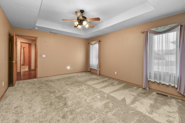 carpeted empty room featuring ceiling fan and a tray ceiling