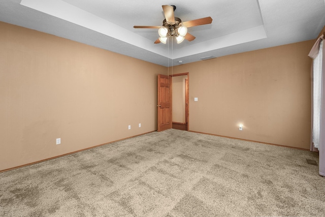 unfurnished room featuring ceiling fan, carpet flooring, and a tray ceiling