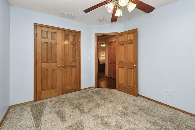 unfurnished bedroom with ceiling fan, dark carpet, and a closet