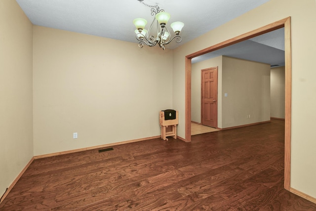 empty room featuring heating unit, a notable chandelier, and dark hardwood / wood-style flooring