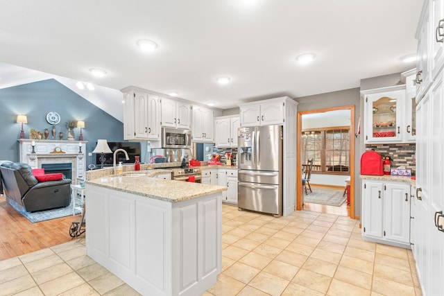 kitchen with white cabinetry, stainless steel appliances, kitchen peninsula, and light stone counters