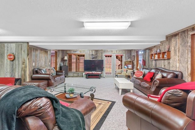 carpeted living room featuring beamed ceiling, a textured ceiling, wooden walls, and french doors