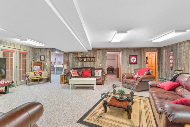 living room with french doors, wooden walls, carpet flooring, and a textured ceiling