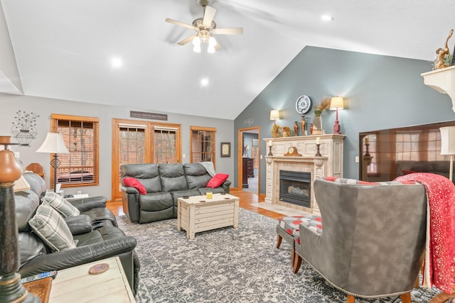 living room featuring a tiled fireplace, vaulted ceiling, hardwood / wood-style floors, and ceiling fan