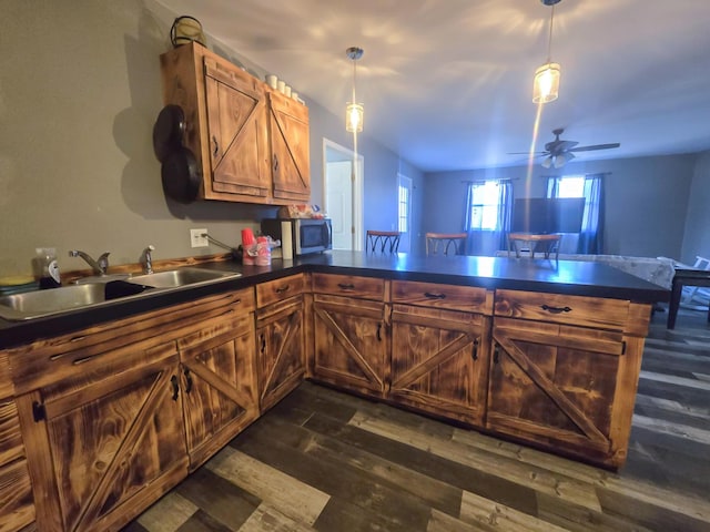 kitchen with hanging light fixtures, sink, dark hardwood / wood-style floors, and kitchen peninsula