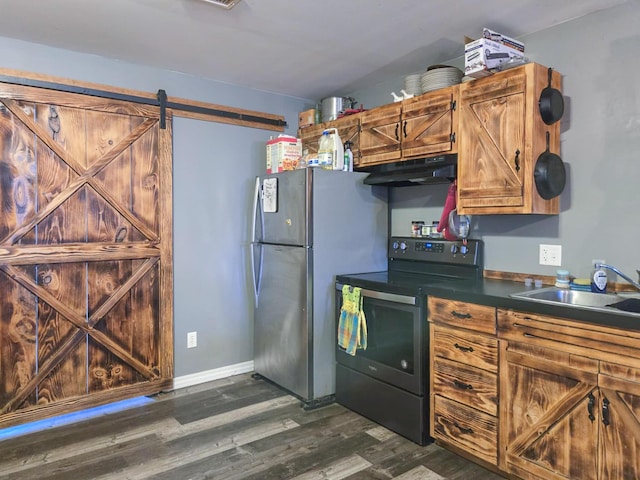 kitchen with a barn door, appliances with stainless steel finishes, sink, and dark wood-type flooring