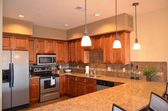 kitchen featuring sink, light stone counters, tasteful backsplash, decorative light fixtures, and stainless steel appliances