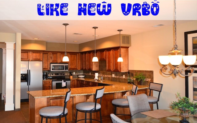 201 Prairie Dunes Dr Unit 1205, Branson, MO 65616 - kitchen with appliances with stainless steel finishes, brown cabinets, a peninsula, and decorative backsplash