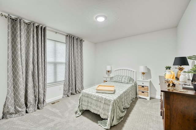 bedroom featuring baseboards, visible vents, and light carpet