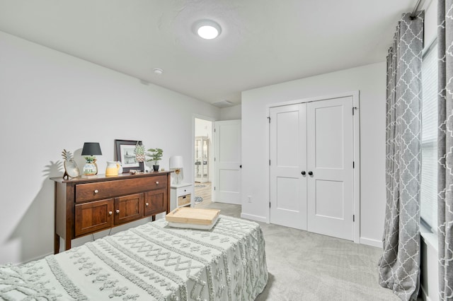 bedroom with a closet, light carpet, and baseboards