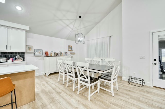 dining room featuring vaulted ceiling, baseboards, light wood finished floors, and a chandelier