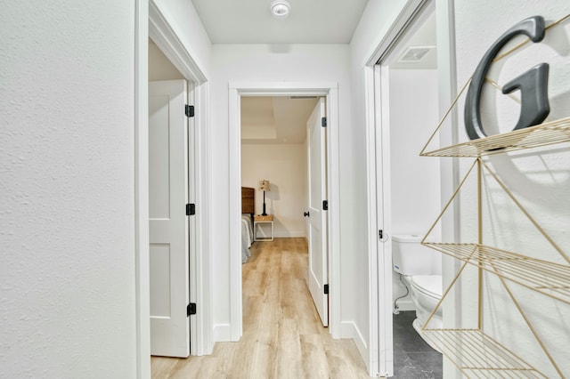 corridor featuring light wood finished floors, visible vents, and baseboards