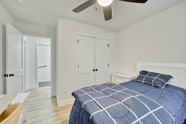 bedroom featuring a ceiling fan, light wood-type flooring, a closet, and baseboards