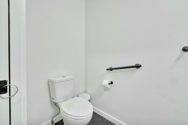 bathroom with tile patterned flooring, toilet, and baseboards