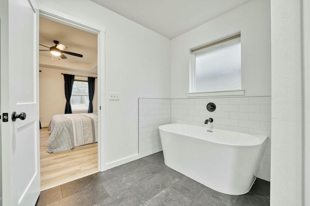 ensuite bathroom with a wainscoted wall, a freestanding bath, tile walls, and ensuite bathroom