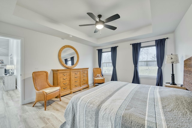 bedroom with ceiling fan, baseboards, a raised ceiling, and wood finished floors