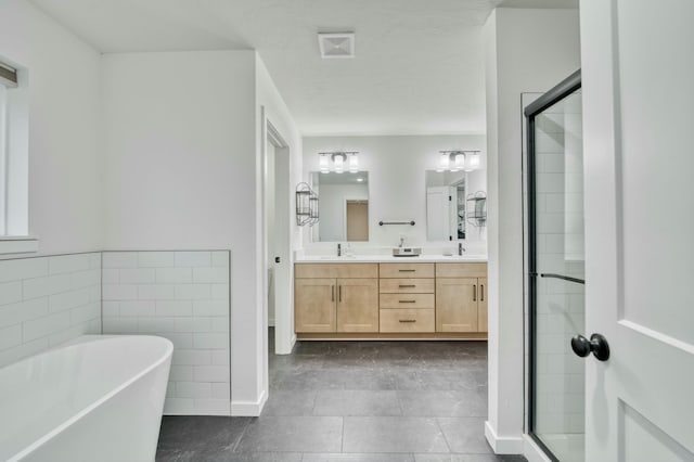 full bathroom with a freestanding bath, double vanity, a stall shower, and a sink