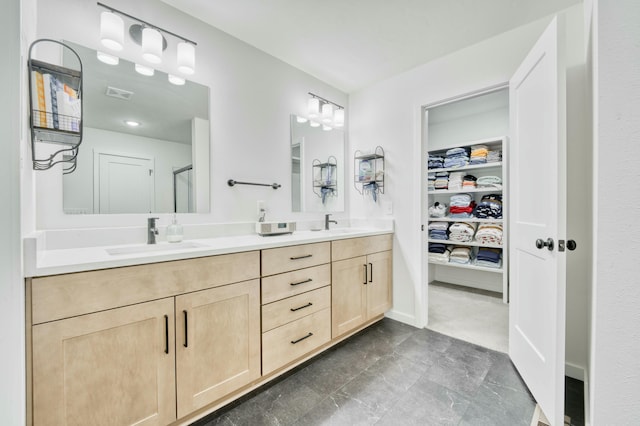 full bathroom with visible vents, double vanity, a sink, a shower stall, and a walk in closet