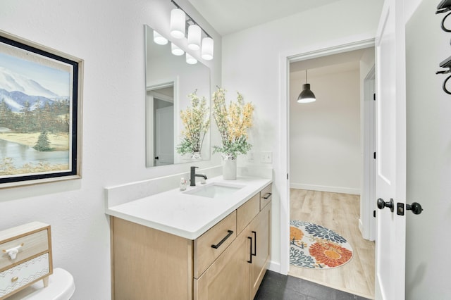 bathroom with vanity, wood finished floors, and baseboards