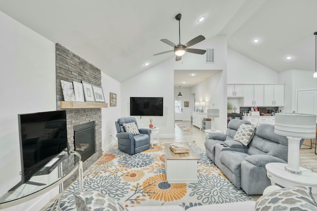 living room featuring a ceiling fan, visible vents, high vaulted ceiling, a fireplace, and light wood-type flooring